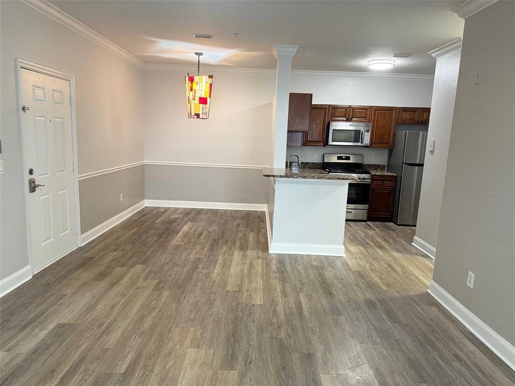 An open-concept dining area flows into a kitchen with dark wood cabinets and stainless appliances — 3367 S KIRKMAN ROAD UNIT 1111, ORLANDO, FL