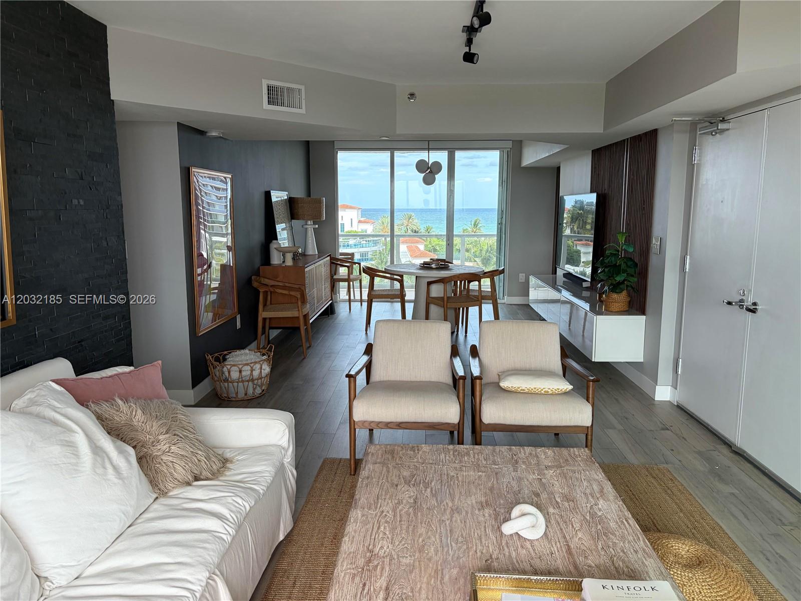 A living and dining area features a white sofa, two armchairs, and ocean views — 5900 Collins Ave # 702, Miami Beach FL 33140, MIAMI BEACH, FL