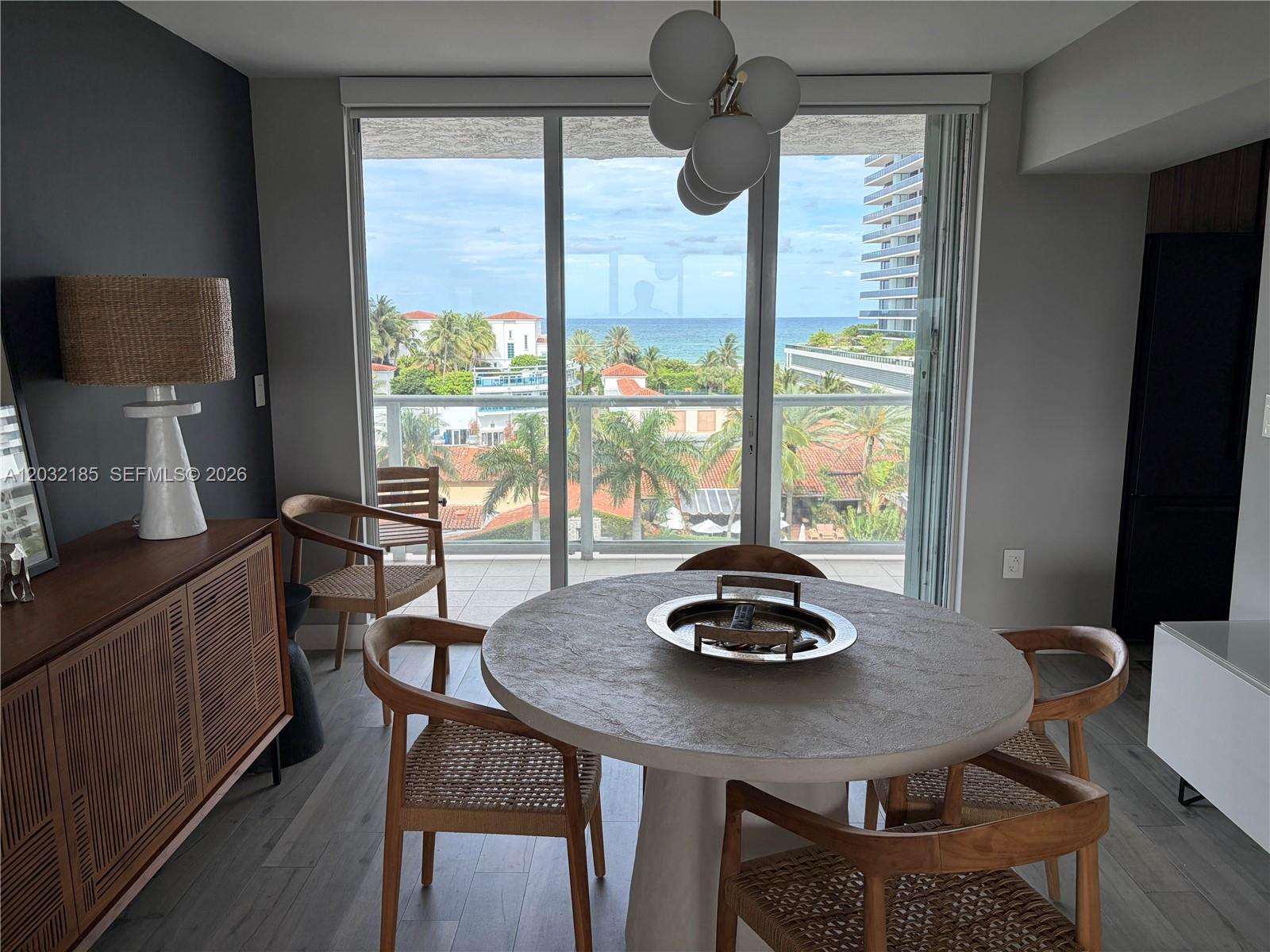 A dining area features a round stone table, wooden chairs, and a balcony with ocean views — 5900 Collins Ave # 702, Miami Beach FL 33140, MIAMI BEACH, FL