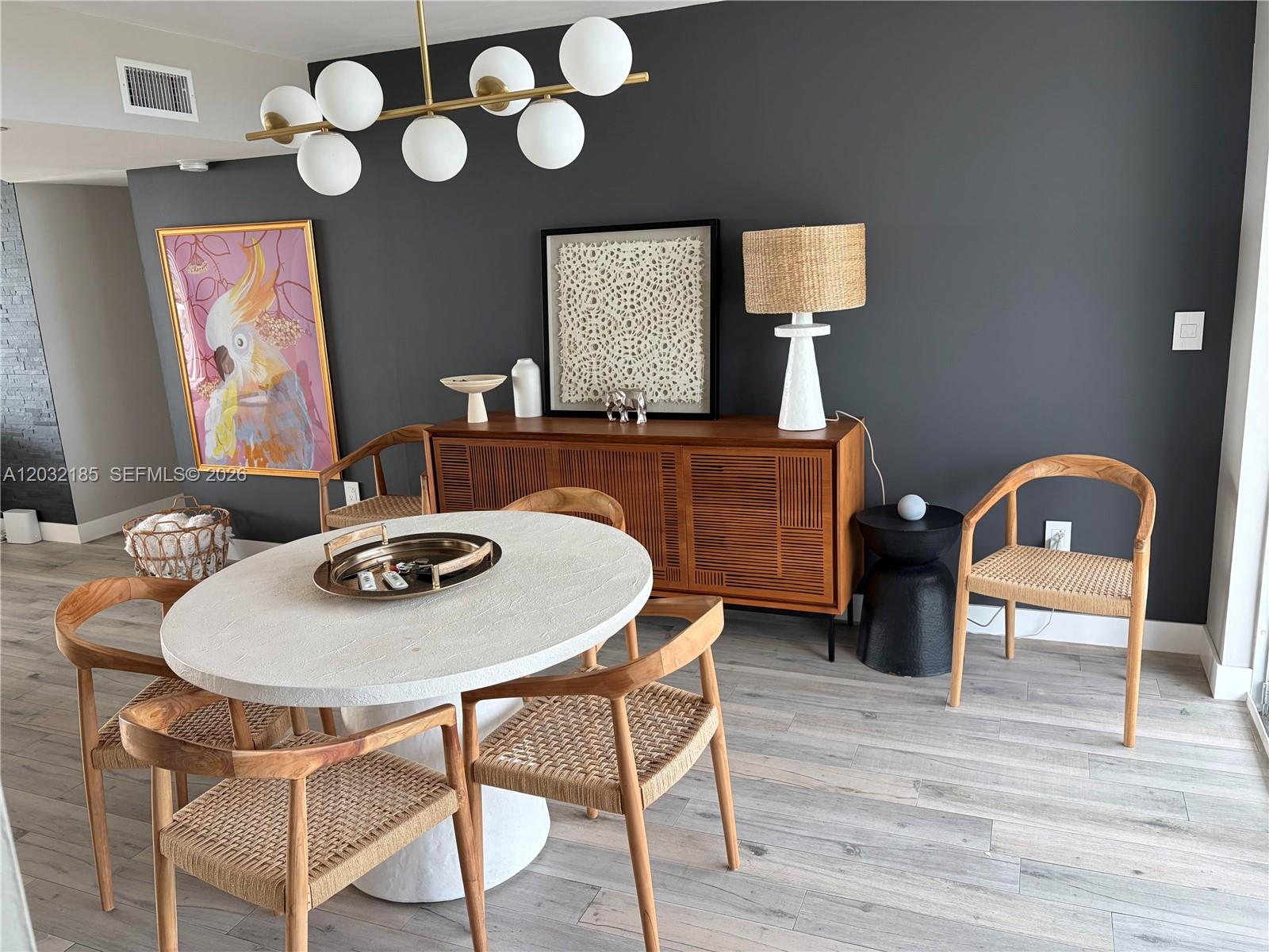 A dining room features a round white table, wooden chairs, and a dark accent wall — 5900 Collins Ave # 702, Miami Beach FL 33140, MIAMI BEACH, FL