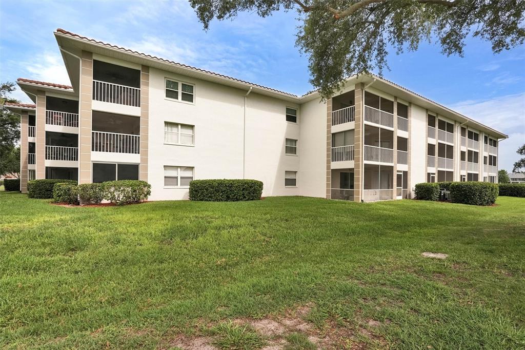 A multi-story apartment building features screened balconies and a large grassy lawn — 6507 STONE RIVER ROAD UNIT 102, BRADENTON, FL