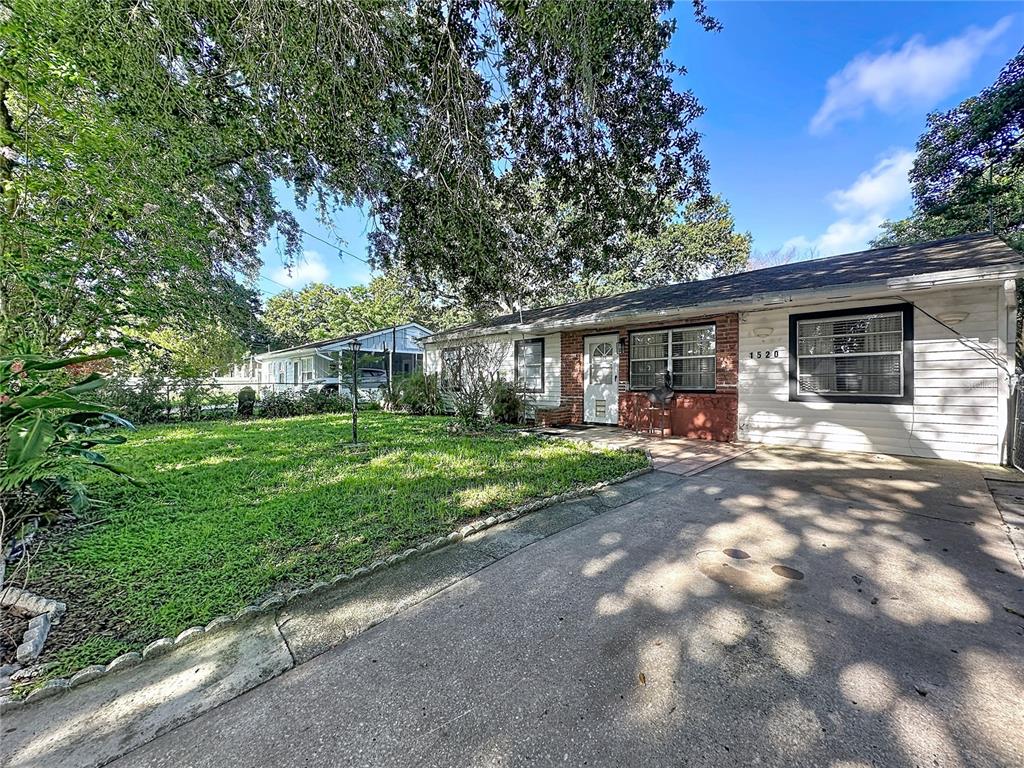 A single-story house with white siding and a concrete driveway sits under large trees — 1520 OVERDALE STREET, ORLANDO, FL
