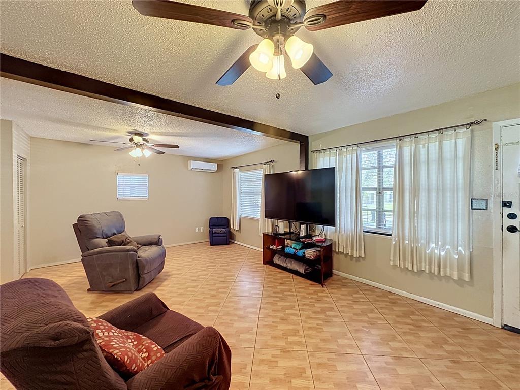 A living room with tile flooring, two ceiling fans, and a large television on a stand — 1520 OVERDALE STREET, ORLANDO, FL