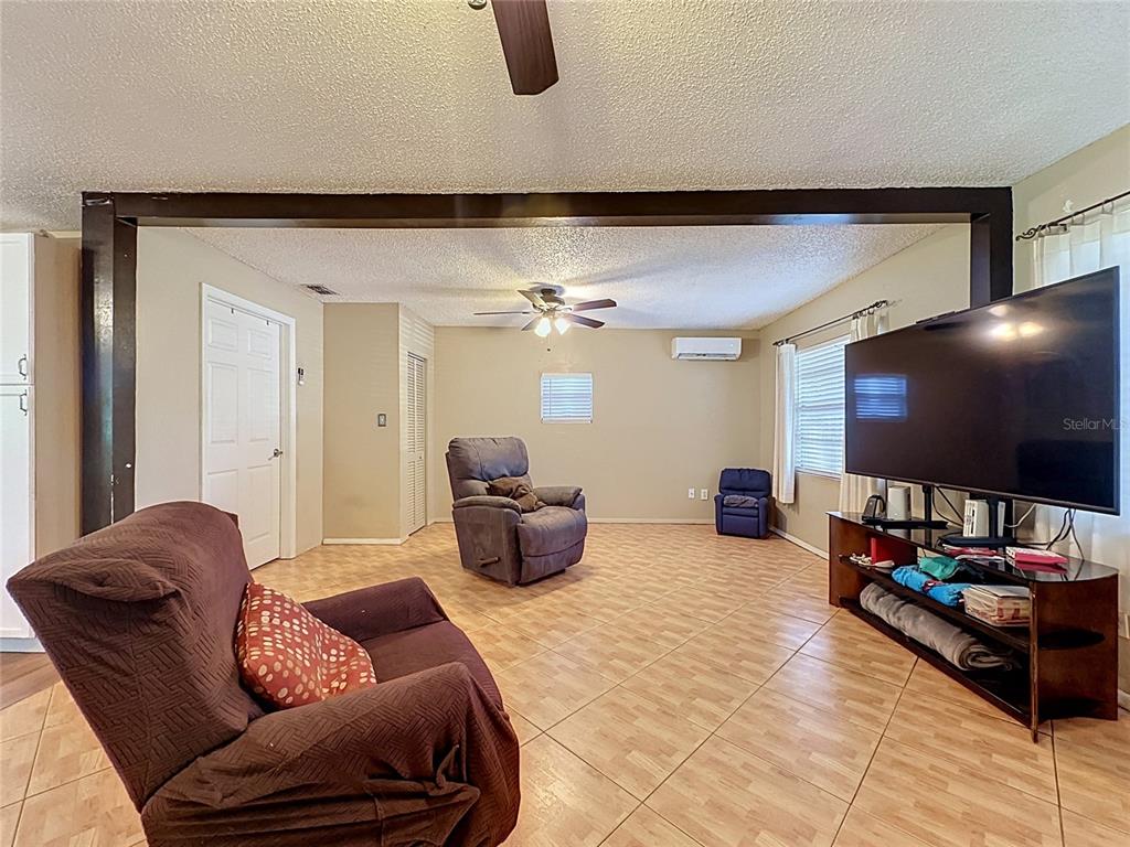 A living room features tile flooring, a ceiling fan, and a large television on a stand — 1520 OVERDALE STREET, ORLANDO, FL
