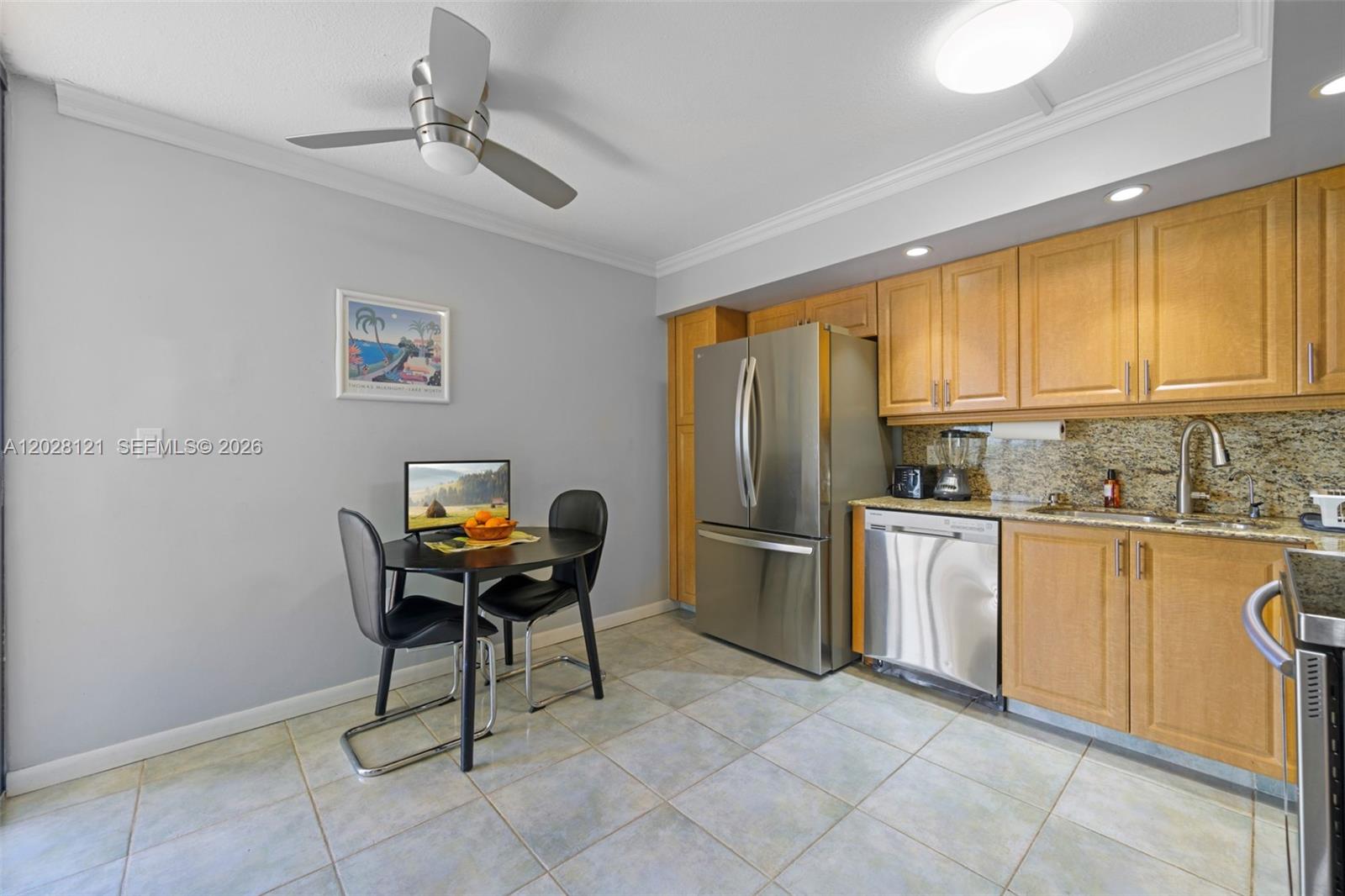 A kitchen features light wood cabinets, stainless steel appliances, granite countertops, and a small dining table — 2804 N 46th Ave # C630, Hollywood FL 33021, HOLLYWOOD, FL