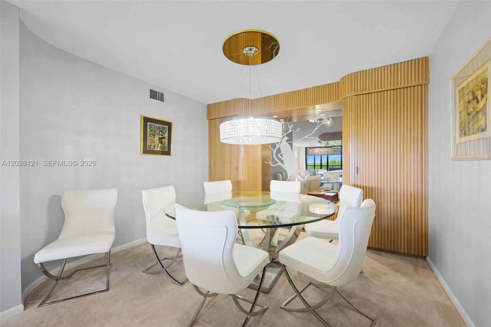 A dining room features a glass table, white chairs, and a wood-paneled accent wall — 2804 N 46th Ave # C630, Hollywood FL 33021, HOLLYWOOD, FL
