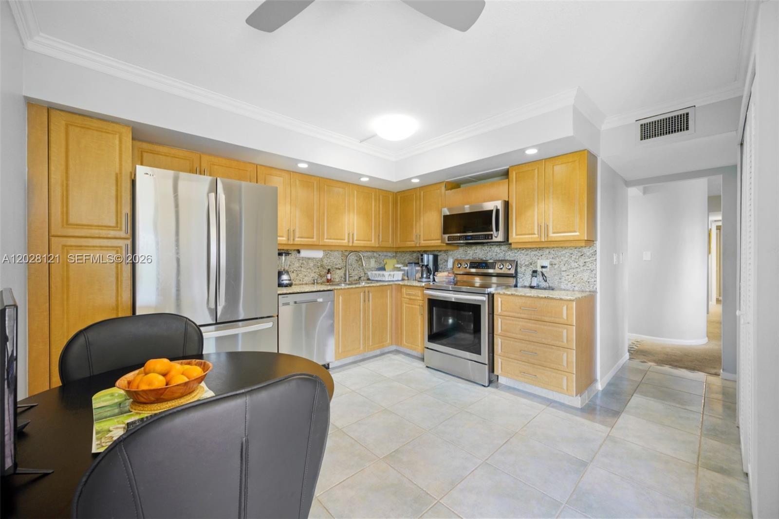 A kitchen features light wood cabinets, stainless steel appliances, granite countertops, and light tile flooring — 2804 N 46th Ave # C630, Hollywood FL 33021, HOLLYWOOD, FL