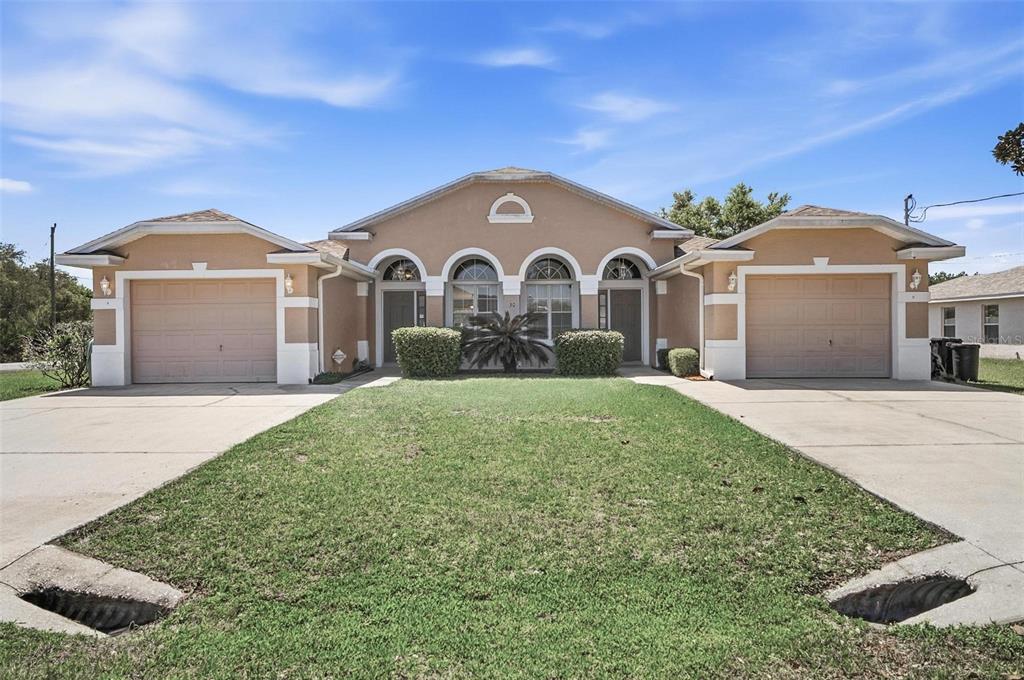 A single-story duplex with two garages, arched entryways, and a shared front lawn — 30 LOUVET LANE, PALM COAST, FL