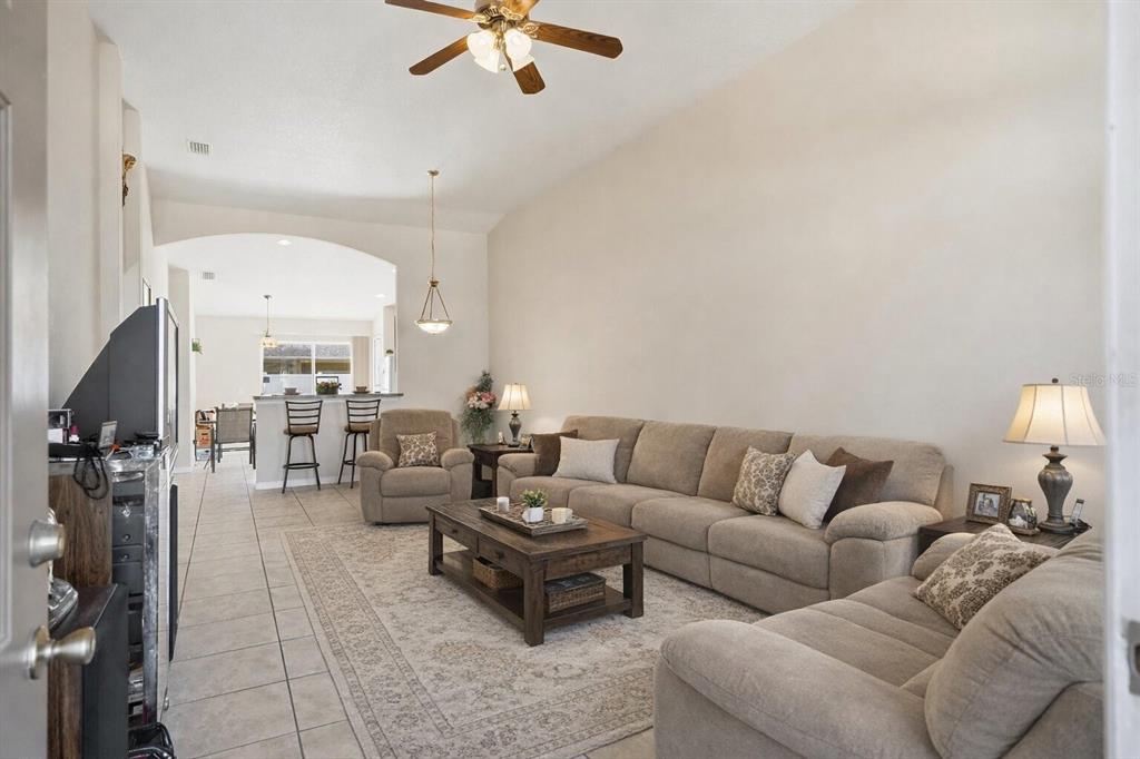 A living room with tile floors, a large beige sectional sofa, and a ceiling fan — 30 LOUVET LANE, PALM COAST, FL
