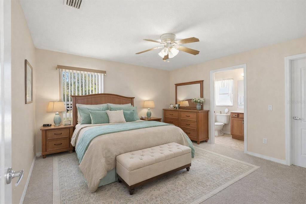 A bedroom features a wooden bed frame, a beige bench, and an attached bathroom — 30 LOUVET LANE, PALM COAST, FL