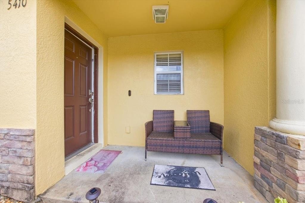 A covered front porch features a brown door, a window, and a wicker bench — 5410 QUARRY ROCK ROAD, LAKELAND, FL
