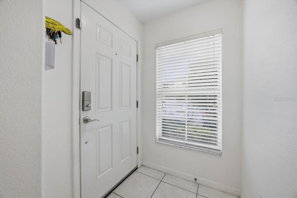 An entryway features a white front door, a window with blinds, and light-colored tile flooring — 5410 QUARRY ROCK ROAD, LAKELAND, FL