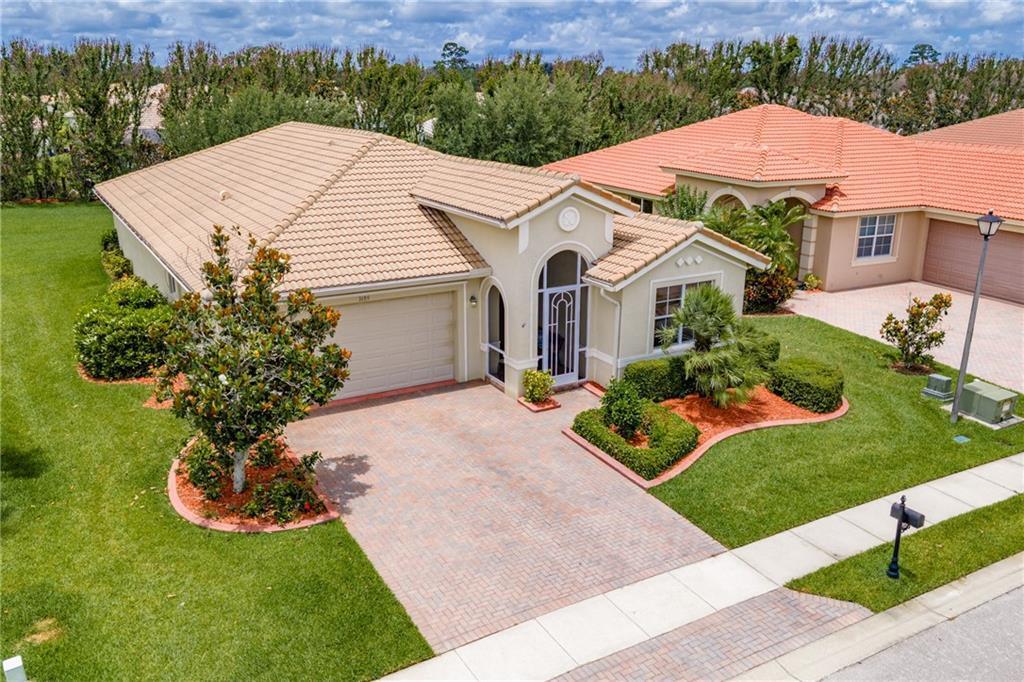 An aerial view shows a single-story house with a tiled roof and a paved driveway — VERO BEACH, FL
