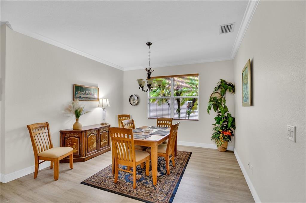A dining room features a wooden table and chairs, a sideboard, and a patterned rug — VERO BEACH, FL