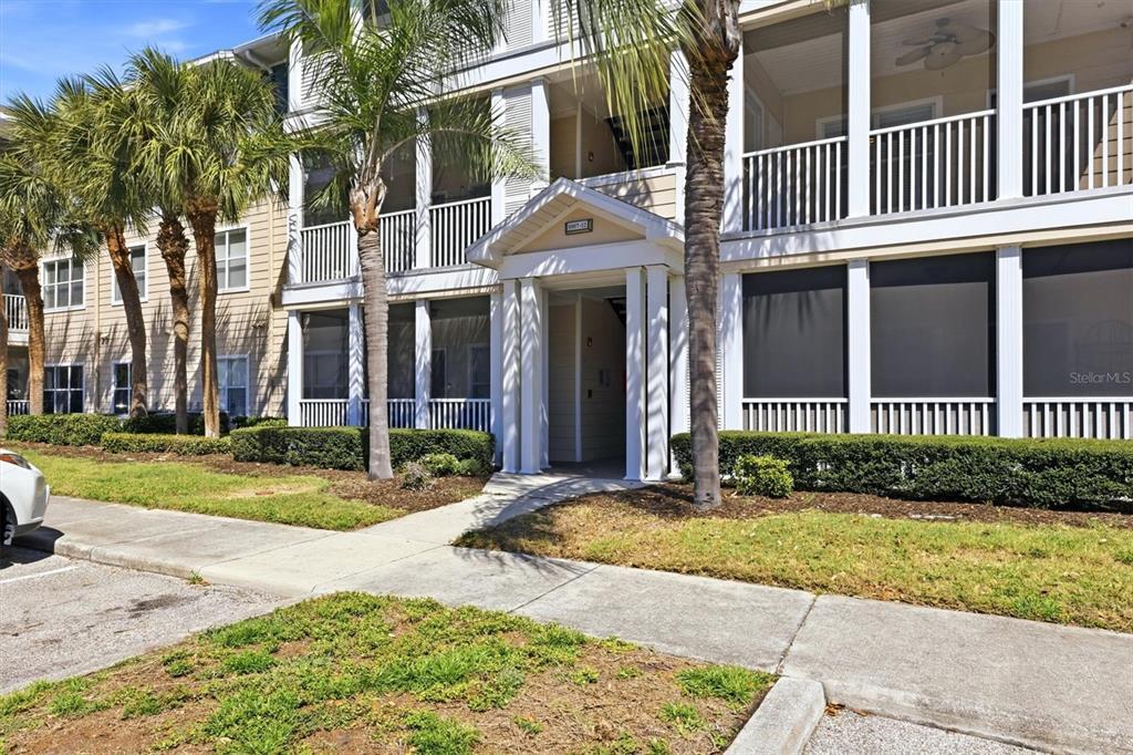 A multi-story apartment building features screened balconies, white railings, and palm trees in front — 4802 51ST STREET W UNIT 1010, BRADENTON, FL