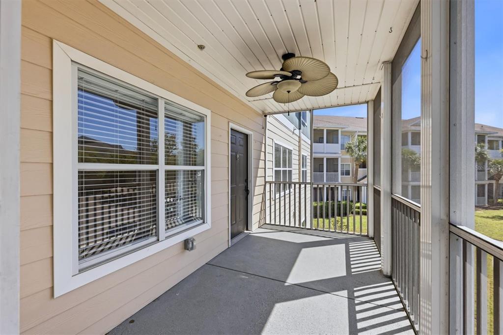 A screened-in balcony features a ceiling fan, a dark door, and a large window — 4802 51ST STREET W UNIT 1010, BRADENTON, FL