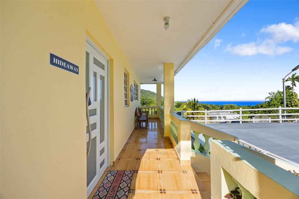 A yellow exterior balcony features tiled flooring, a glass door, and a view of the ocean — Carr 3 CAMINO COOPERATIVO, PATILLAS, PR