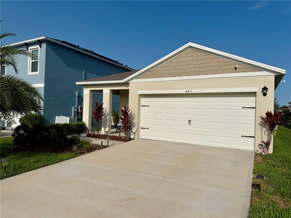 A single-story house with a beige stucco exterior, a two-car garage, and a covered entryway — 463 LIU LANE, DELAND, FL