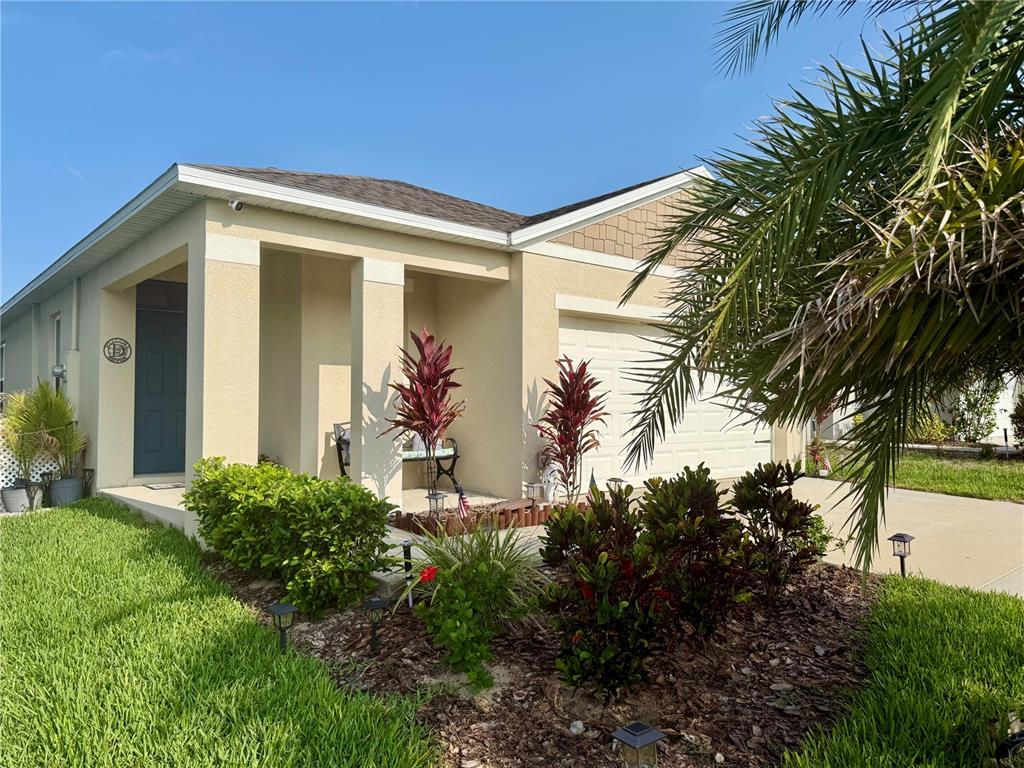 A single-story house with a beige stucco exterior, a covered entryway, and a front garden — 463 LIU LANE, DELAND, FL
