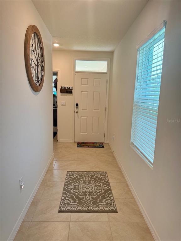 A tiled entryway features a white front door, a window with blinds, and wall decor — 463 LIU LANE, DELAND, FL