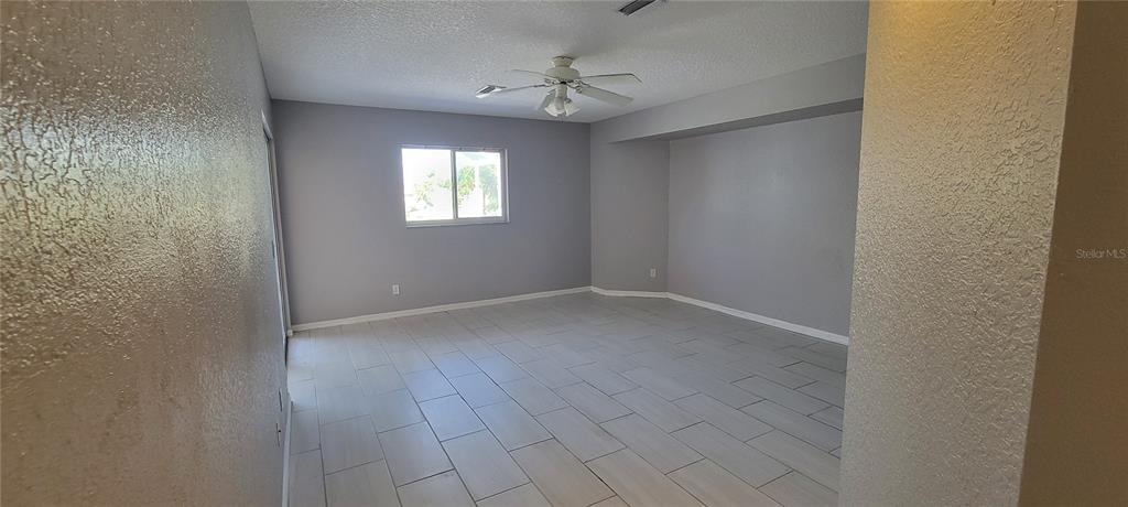 An empty room features light gray walls, white tile flooring, and a ceiling fan — 4147 BULA LANE, NORTH PORT, FL
