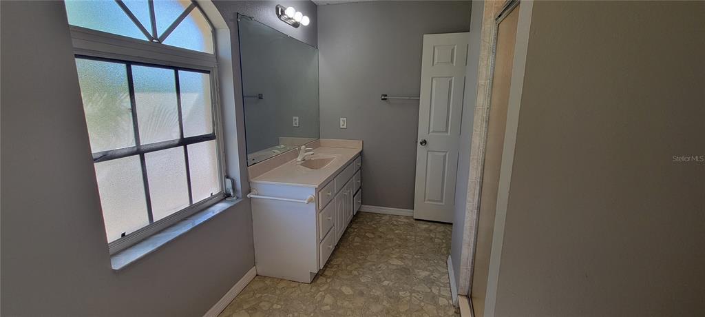 A bathroom features a single-sink vanity, a large mirror, and a window with frosted glass — 4147 BULA LANE, NORTH PORT, FL