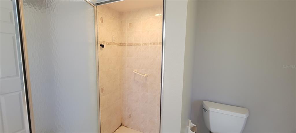 A bathroom features a tiled walk-in shower with a glass door and a white toilet — 4147 BULA LANE, NORTH PORT, FL