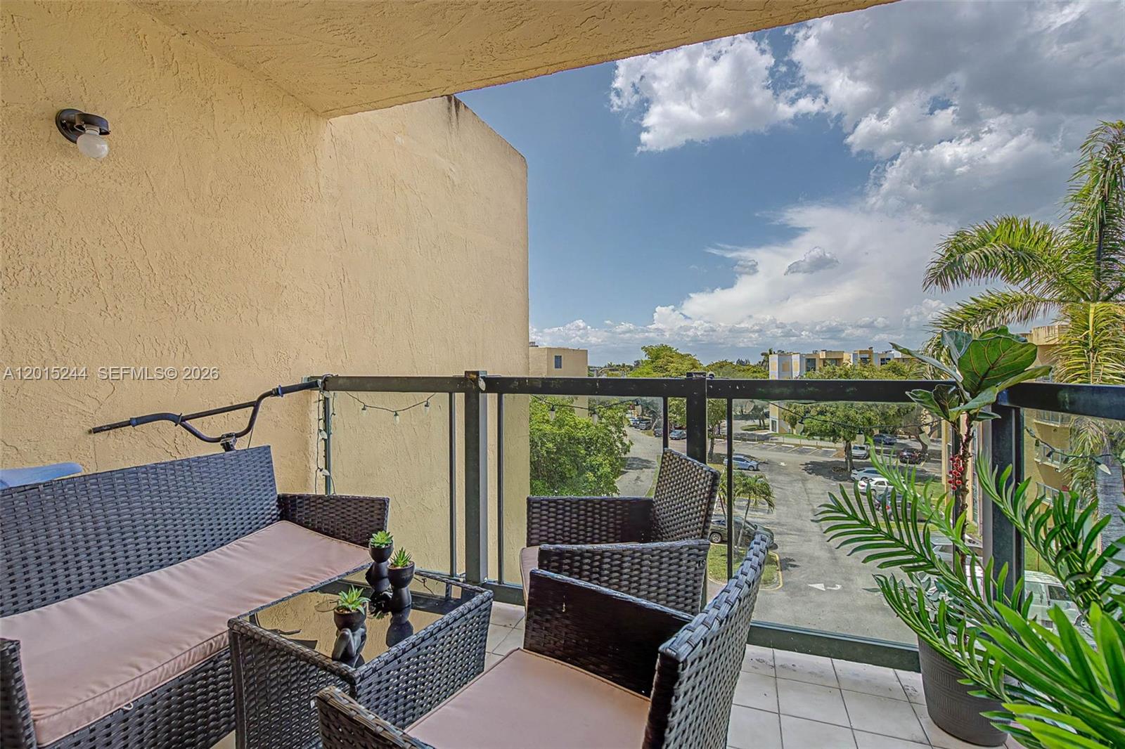 A balcony features wicker patio furniture, a small glass-topped table, and a view of parking — 11790 SW 18th St # 3, Miami FL 33175, MIAMI, FL