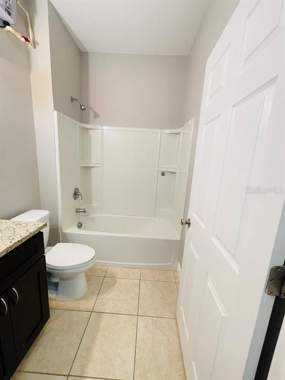 A bathroom features a white tub-shower combo, a toilet, and a dark wood vanity — 1601 CUMIN DRIVE, KISSIMMEE, FL
