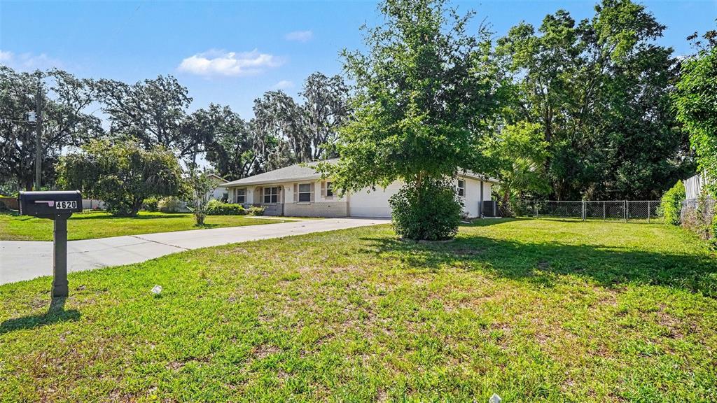 A single-story house with a concrete driveway and a large tree in the front yard — 4620 NE 8TH STREET, OCALA, FL