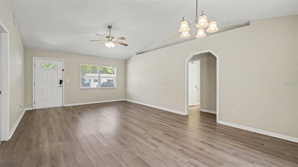 A living room with light-colored walls, wood-look flooring, a ceiling fan, and a chandelier — 4620 NE 8TH STREET, OCALA, FL