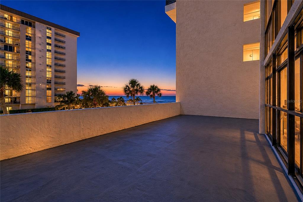 A spacious balcony with a gray floor overlooks the ocean at sunset — 1100 BENJAMIN FRANKLIN DRIVE UNIT 305, SARASOTA, FL