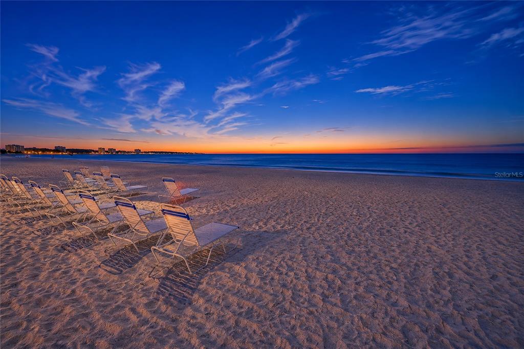 A row of beach chairs sits on a sandy shore at sunset near the ocean — 1100 BENJAMIN FRANKLIN DRIVE UNIT 305, SARASOTA, FL