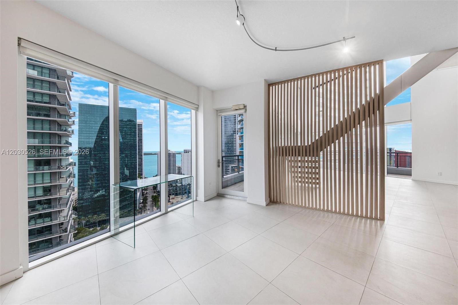 A bright room features white tile floors, a glass desk, and a wooden slat partition — 60 SW 13th St # 2600, Miami FL 33130, MIAMI, FL