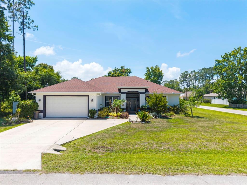 A single-story house with a white exterior, a two-car garage, and a brown shingled roof — 2 EDGEMONT PLACE, PALM COAST, FL