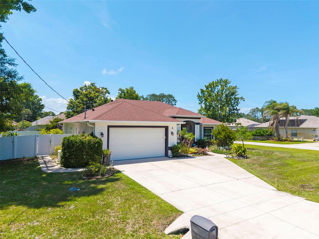 A single-story house with a white exterior, a two-car garage, and a brown shingled roof — 2 EDGEMONT PLACE, PALM COAST, FL