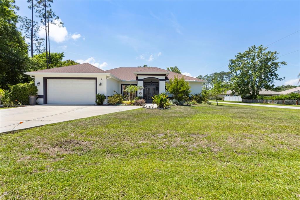 A single-story house with a white exterior, a two-car garage, and a large front lawn — 2 EDGEMONT PLACE, PALM COAST, FL