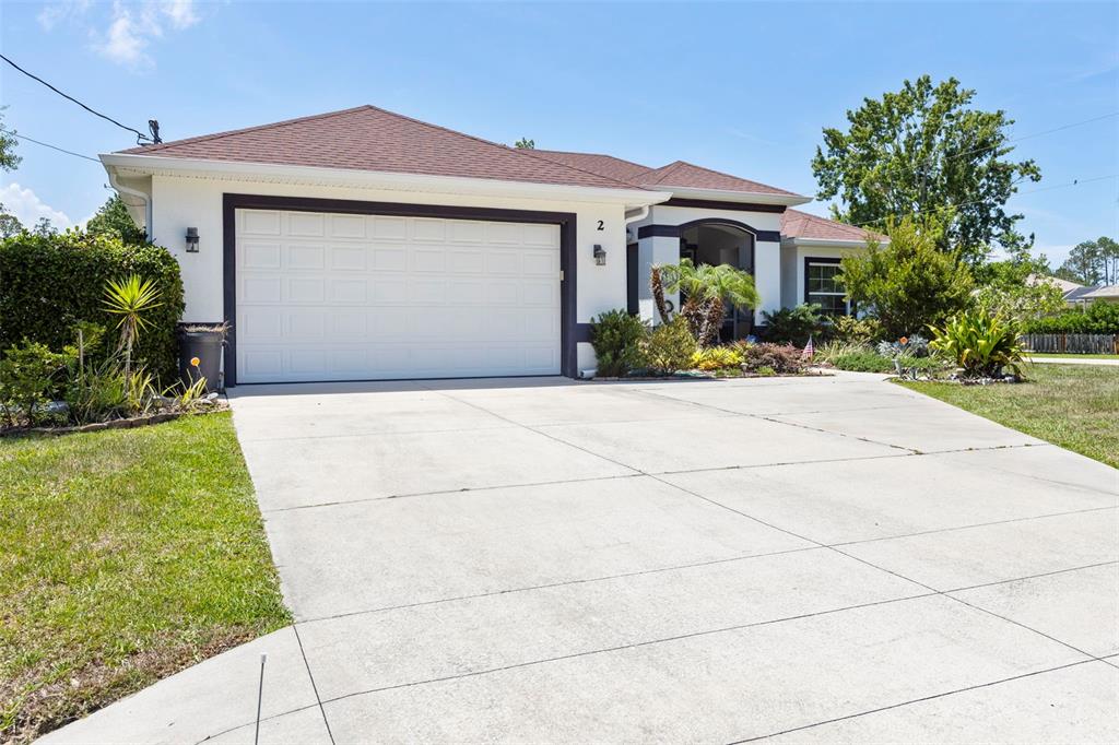 A single-story house with a white exterior, dark trim, and a two-car garage — 2 EDGEMONT PLACE, PALM COAST, FL
