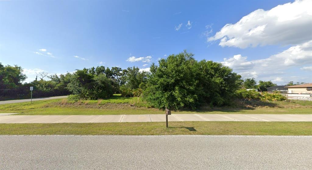 A vacant, grassy lot with mature trees and a sidewalk along a paved road — 10420 GULFSTREAM BOULEVARD, ENGLEWOOD, FL