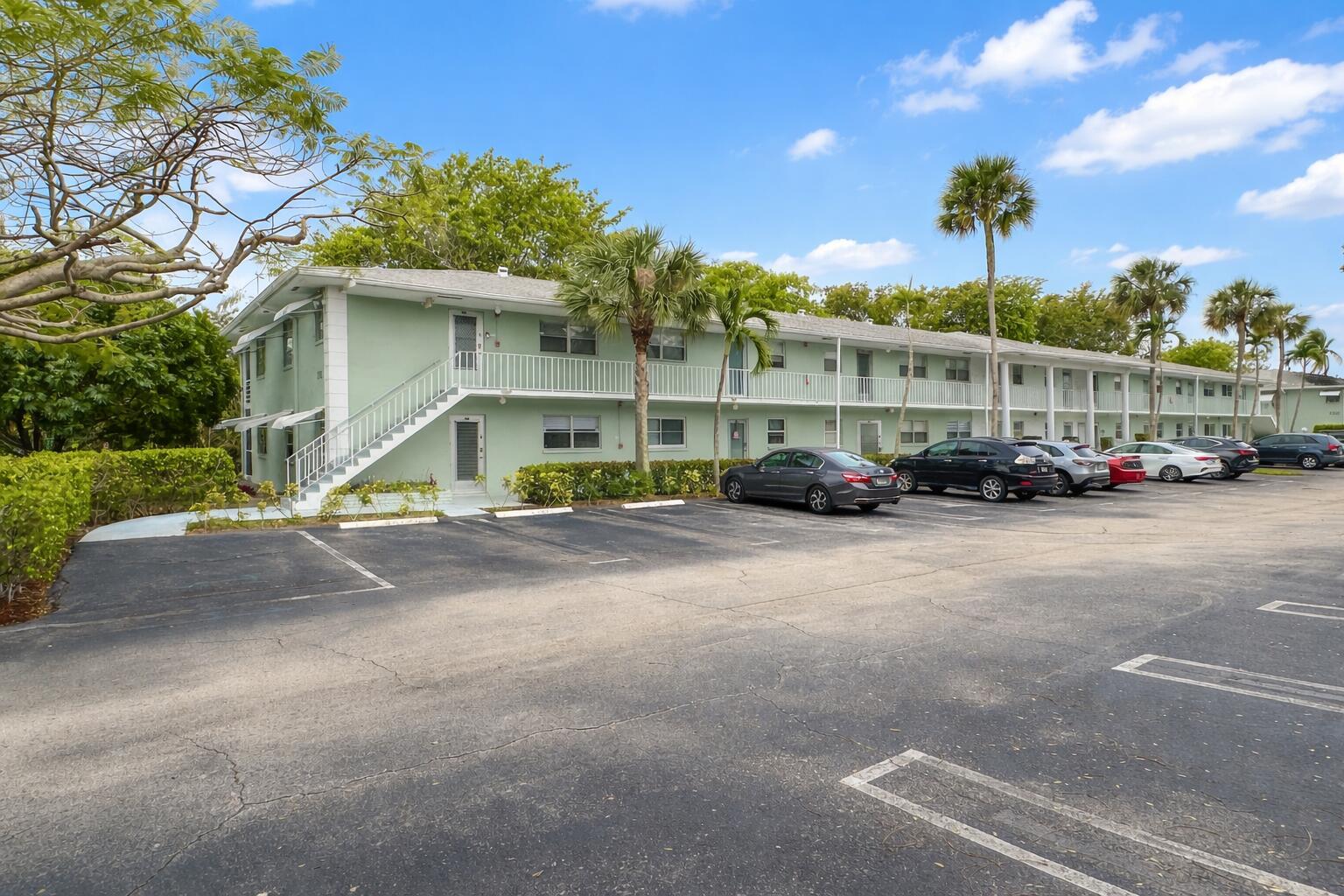 A multi-story, light green apartment building features an exterior staircase and a paved parking lot — 2740 SW 22nd Avenue # 1605, Delray Beach FL 33445, DELRAY BEACH, FL