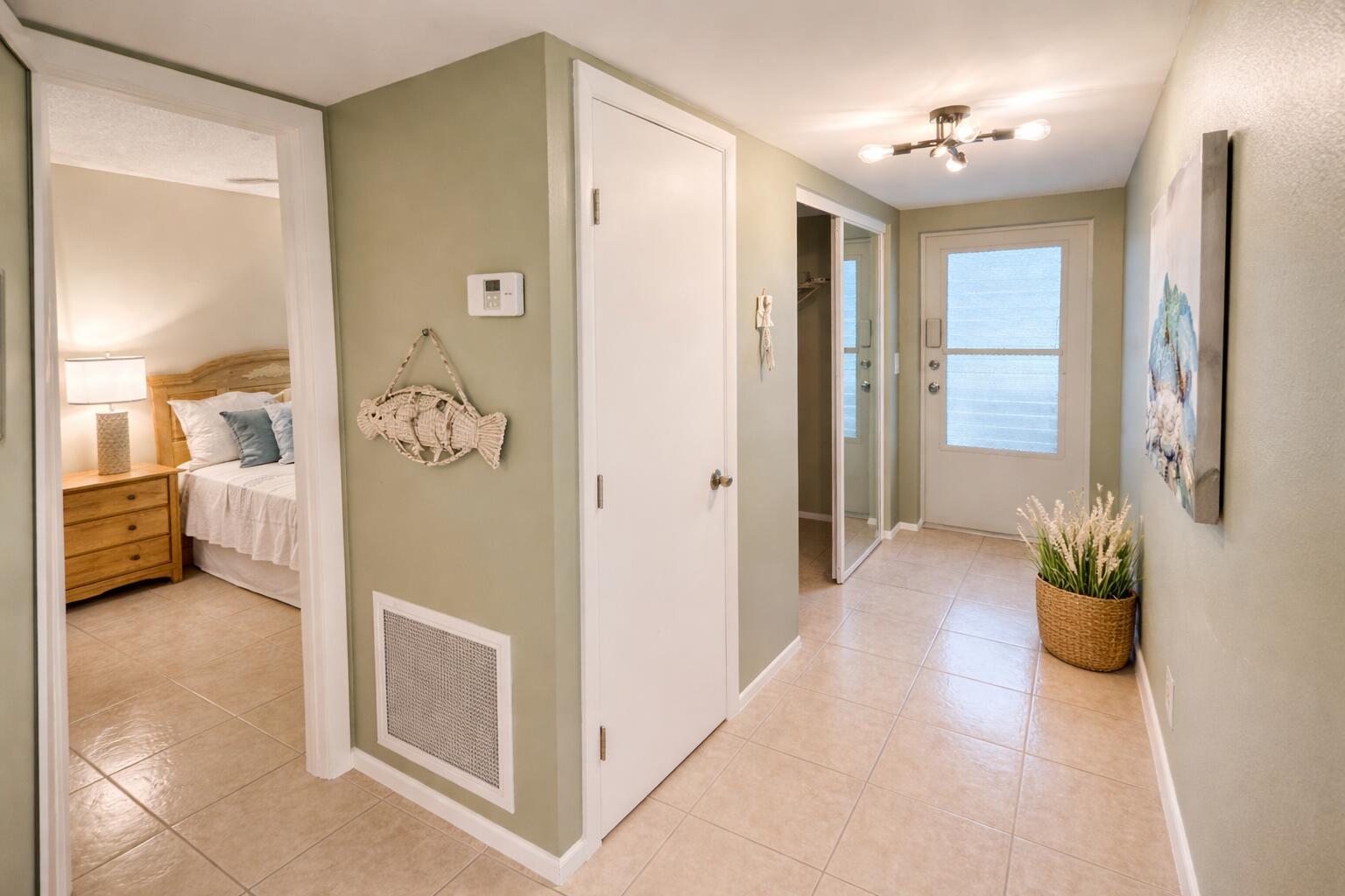 A hallway with light green walls, tiled floors, a white door, and a bedroom entrance — 2740 SW 22nd Avenue # 1605, Delray Beach FL 33445, DELRAY BEACH, FL