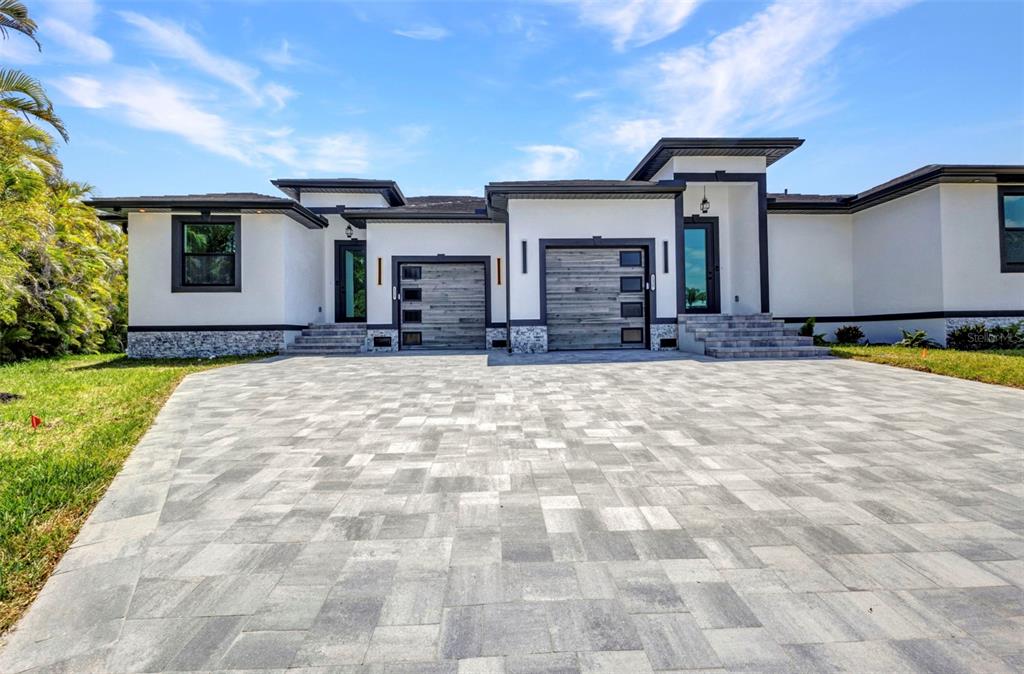 A modern single-story house with a paved driveway, two garage doors, and white stucco walls — 1327 WESLEY DRIVE, PUNTA GORDA, FL