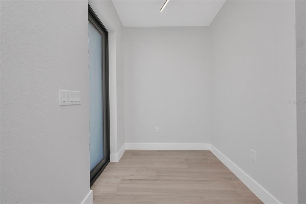 A small, empty room with light gray walls, wood-look flooring, and a sliding glass door — 1327 WESLEY DRIVE, PUNTA GORDA, FL