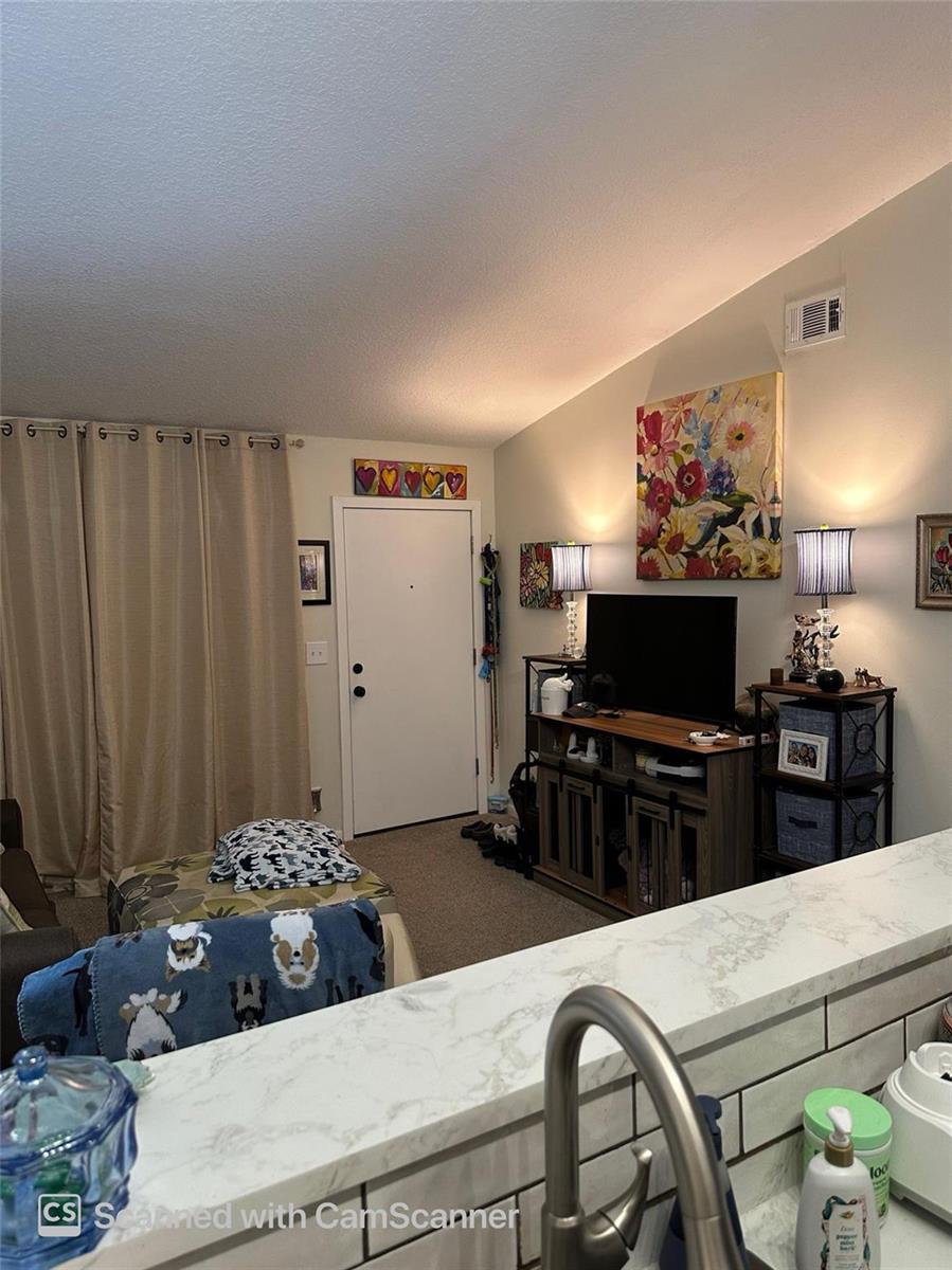 A living room features a television console, floral wall art, and a sliding glass door — 6512 Chasewood Drive # H, Jupiter FL 33458, JUPITER, FL