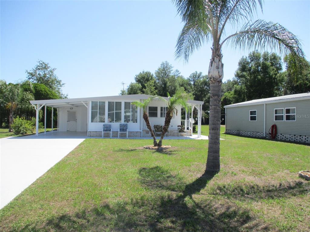A white mobile home with a carport and a palm tree in the front yard — 3734 CASTLE DRIVE, ZEPHYRHILLS, FL