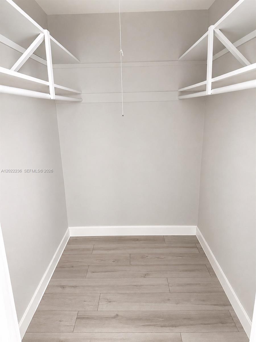 A walk-in closet features light gray walls, white shelving, and wood-look flooring — 500 13th St # 7, Miami Beach FL 33139, MIAMI BEACH, FL