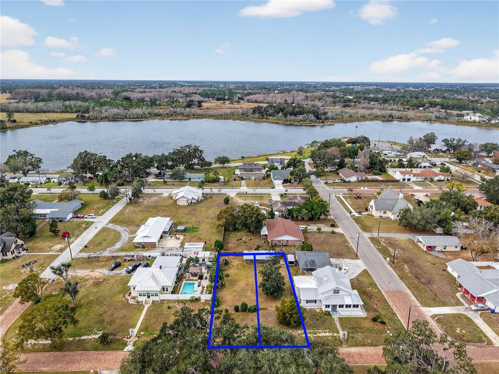 A large, grassy backyard features a clothesline, mature trees, and a white fence — XXX S INDIANA AVE, GROVELAND, FL