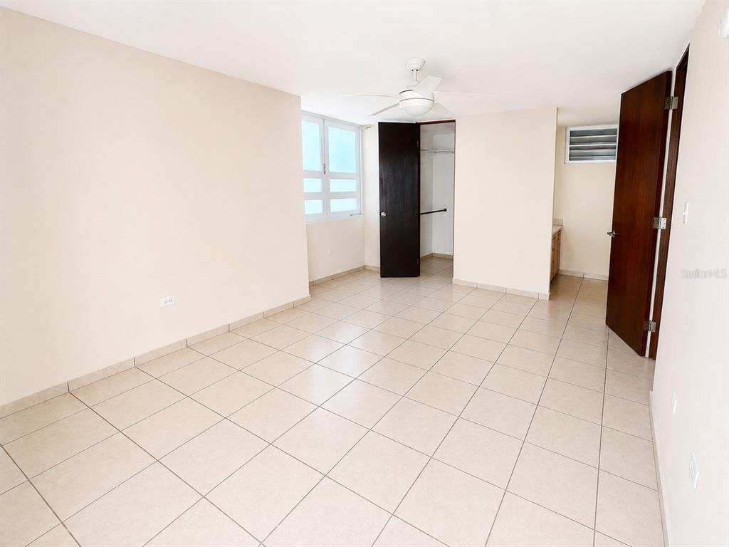 An empty bedroom features light-colored tile flooring, a ceiling fan, and a walk-in closet — L-143 URB PALACIOS DEL PR CALLE PACIFICO, JUANA DIAZ, PR