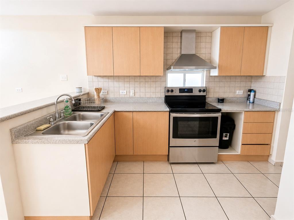 A kitchen features light wood cabinets, stainless steel appliances, a double sink, and tiled flooring — L-143 URB PALACIOS DEL PR CALLE PACIFICO, JUANA DIAZ, PR