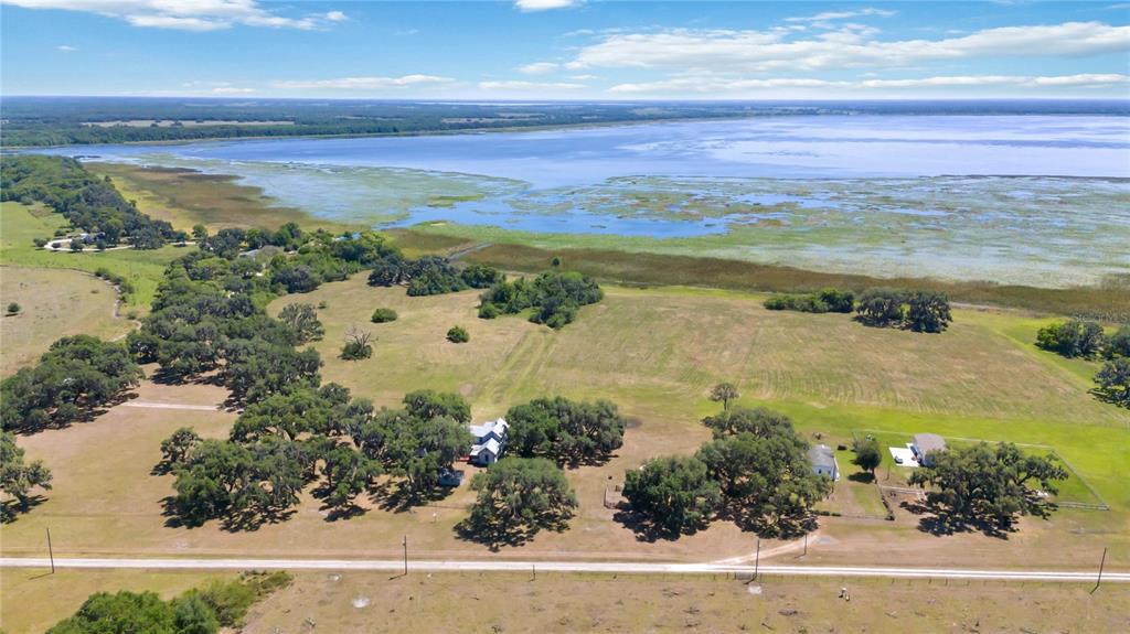 An aerial view shows a rural property with several houses, scattered trees, and a large lake — 3650 LAKE TOHOPEKALIGA ROAD, ST CLOUD, FL